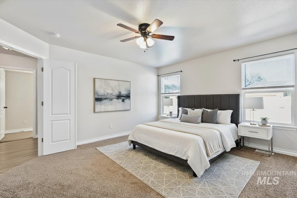 Carpeted bedroom with a ceiling fan and a textured ceiling