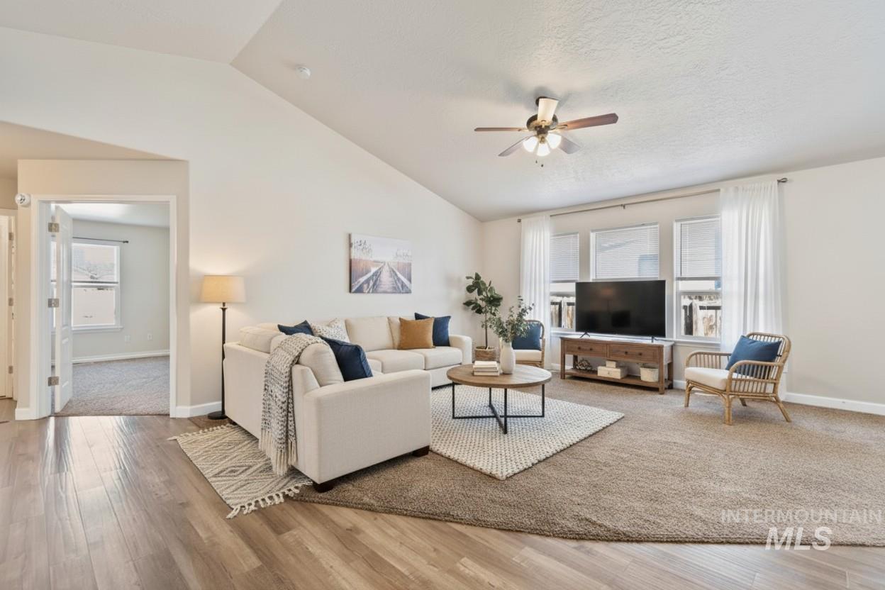 Living area featuring vaulted ceiling, ceiling fan, and light wood-style floors