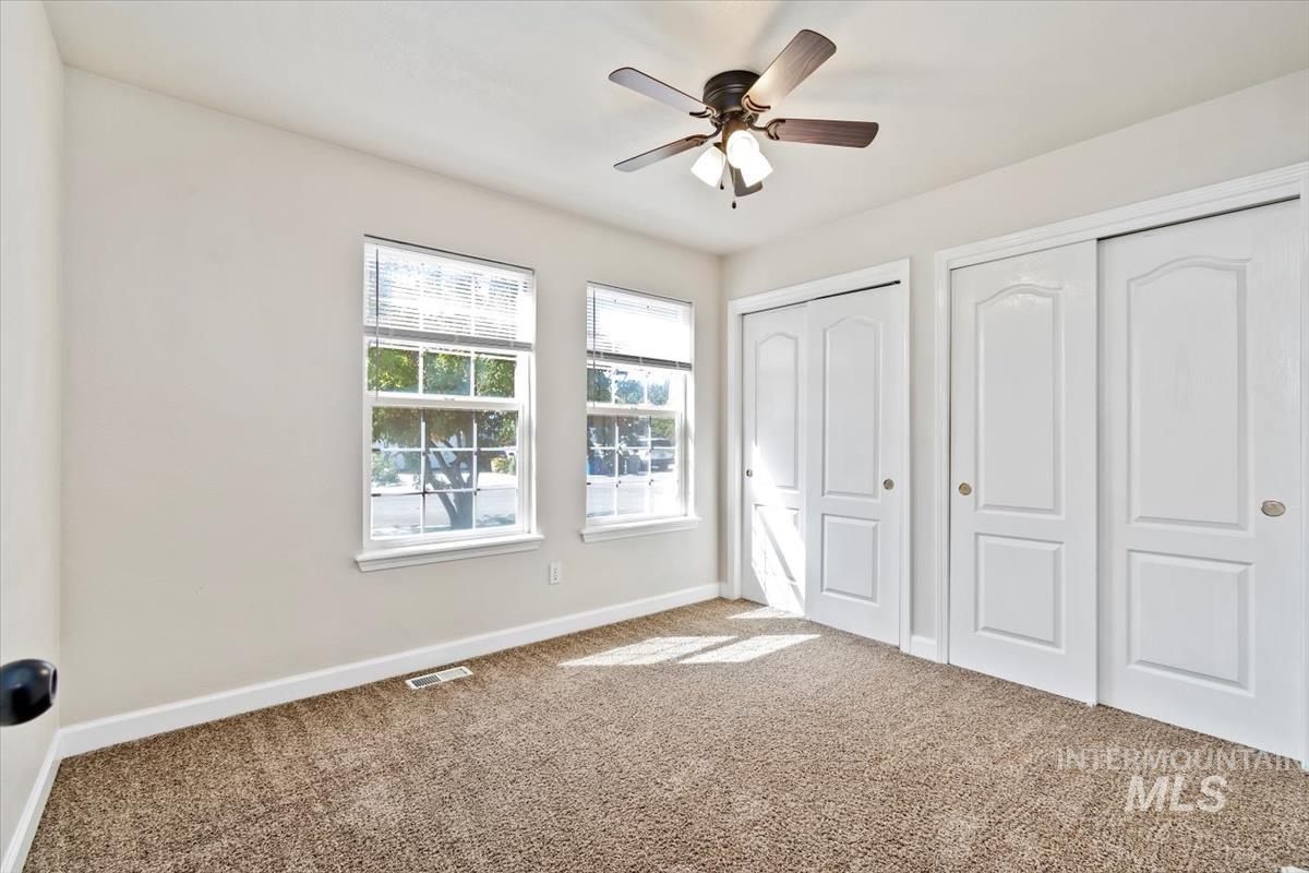 Unfurnished bedroom featuring two closets, carpet, and a ceiling fan