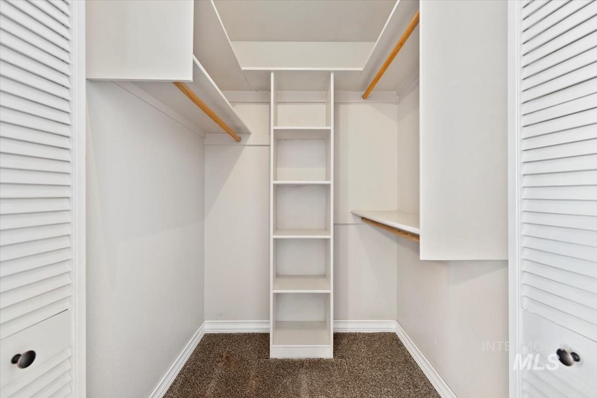Walk in closet with dark colored carpet