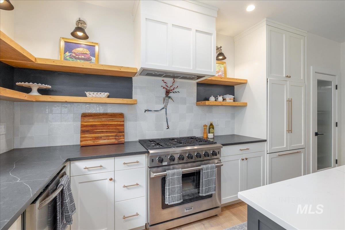 Kitchen with open shelves, stainless steel appliances, white cabinets, backsplash, and recessed lighting