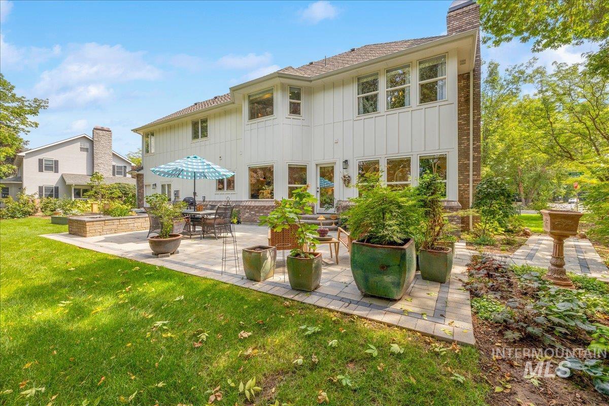 Rear view of house with board and batten siding, a patio, a yard, and a chimney