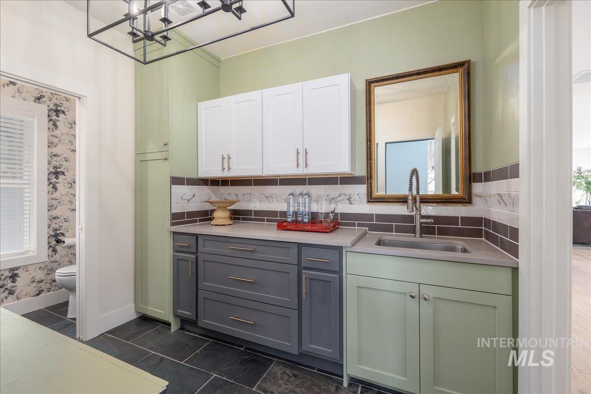 Kitchen with white cabinetry, tasteful backsplash, wallpapered walls, and light stone countertops