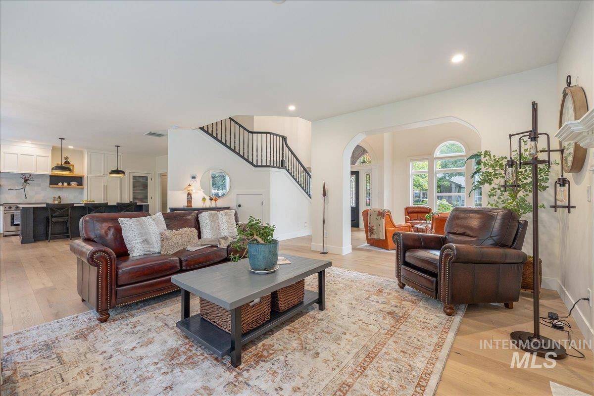 Living area with light wood-style flooring, stairs, recessed lighting, and arched walkways