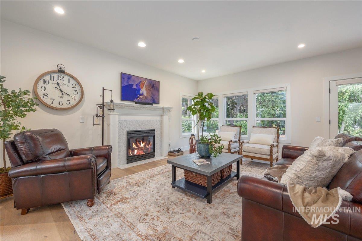 Living room featuring light wood-style floors, recessed lighting, and a fireplace with flush hearth