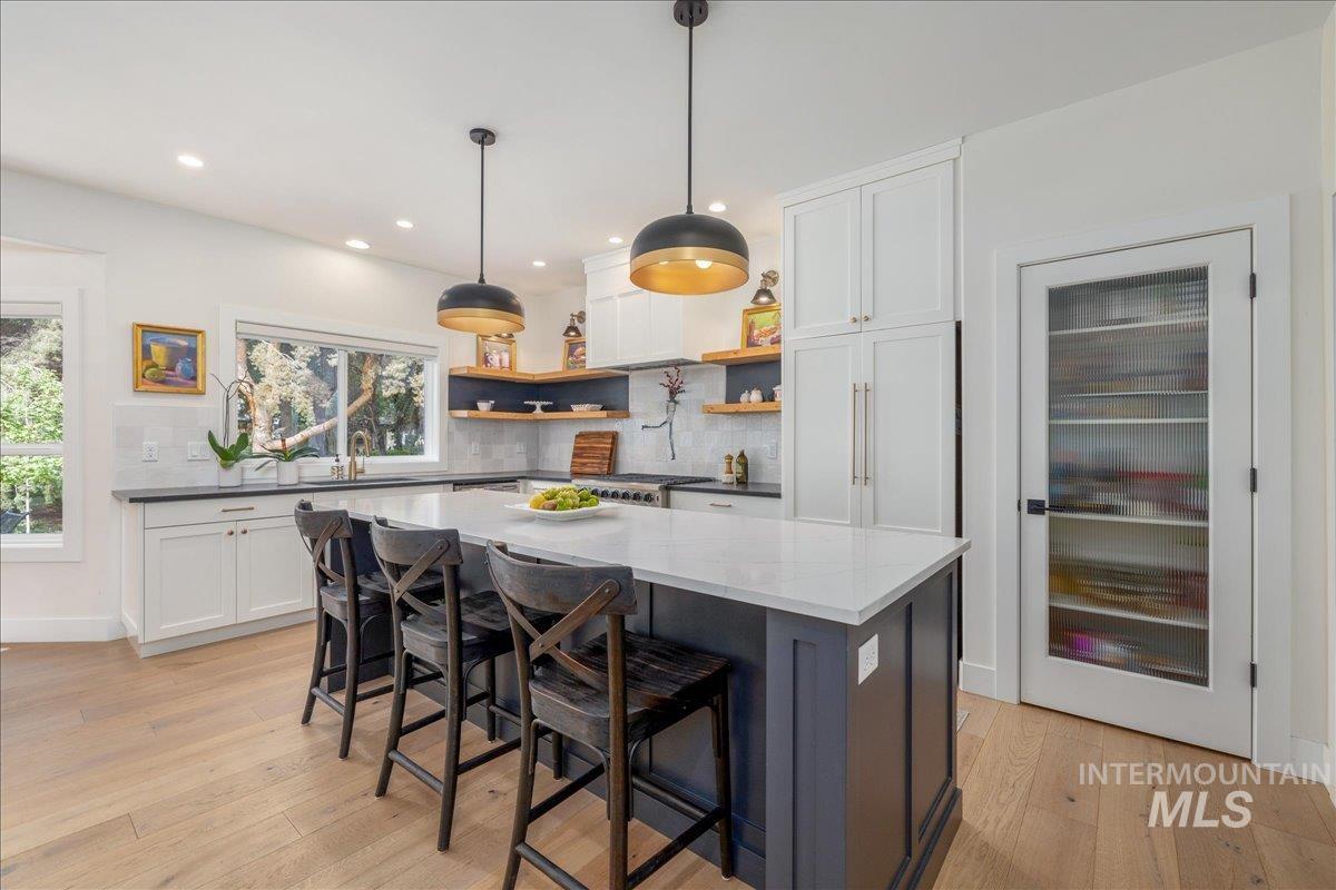 Kitchen featuring decorative backsplash, hanging light fixtures, light wood-style flooring, a breakfast bar, and recessed lighting