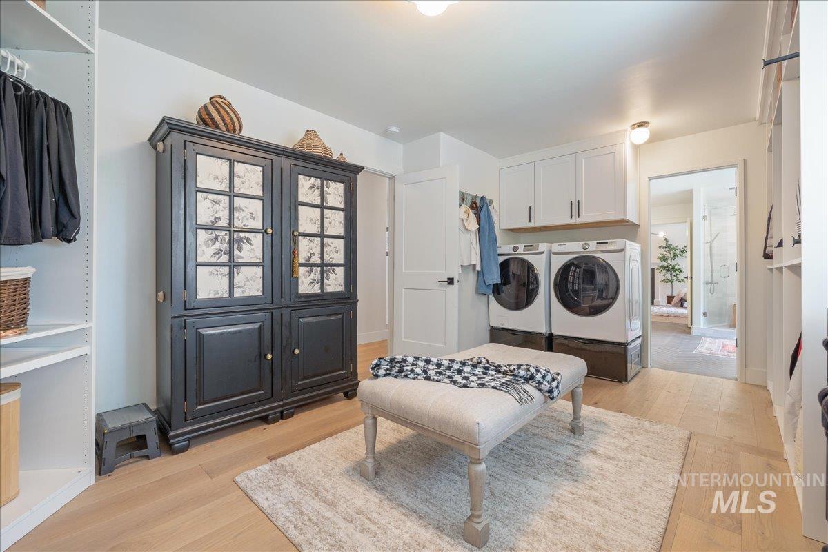 Laundry area with light wood-type flooring, washer and clothes dryer, and cabinet space