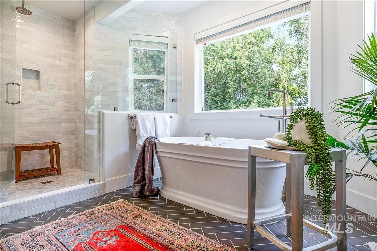 Bathroom featuring a freestanding bath, a stall shower, and dark tile patterned flooring