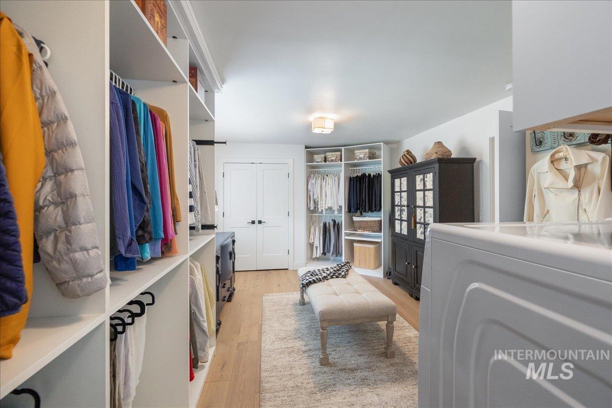 Walk in closet with washer / dryer and light wood-style flooring