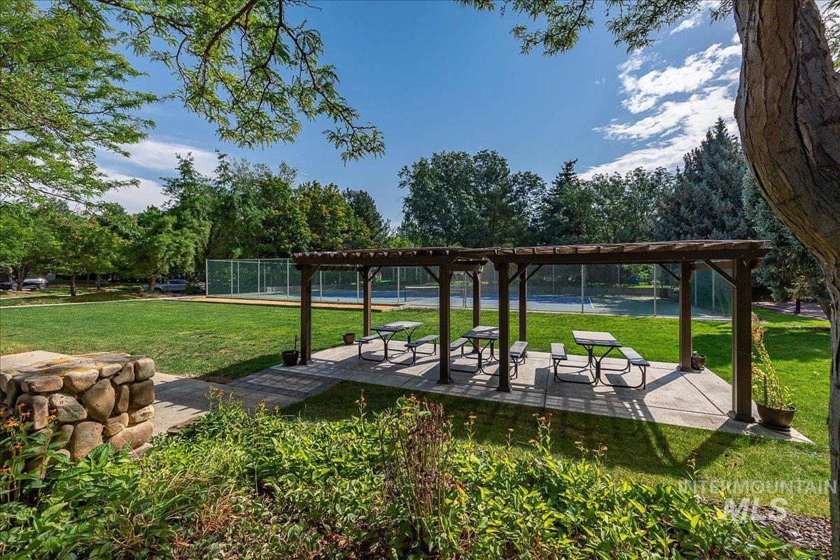 View of home's community with a patio, view of wooded area, and a tennis court