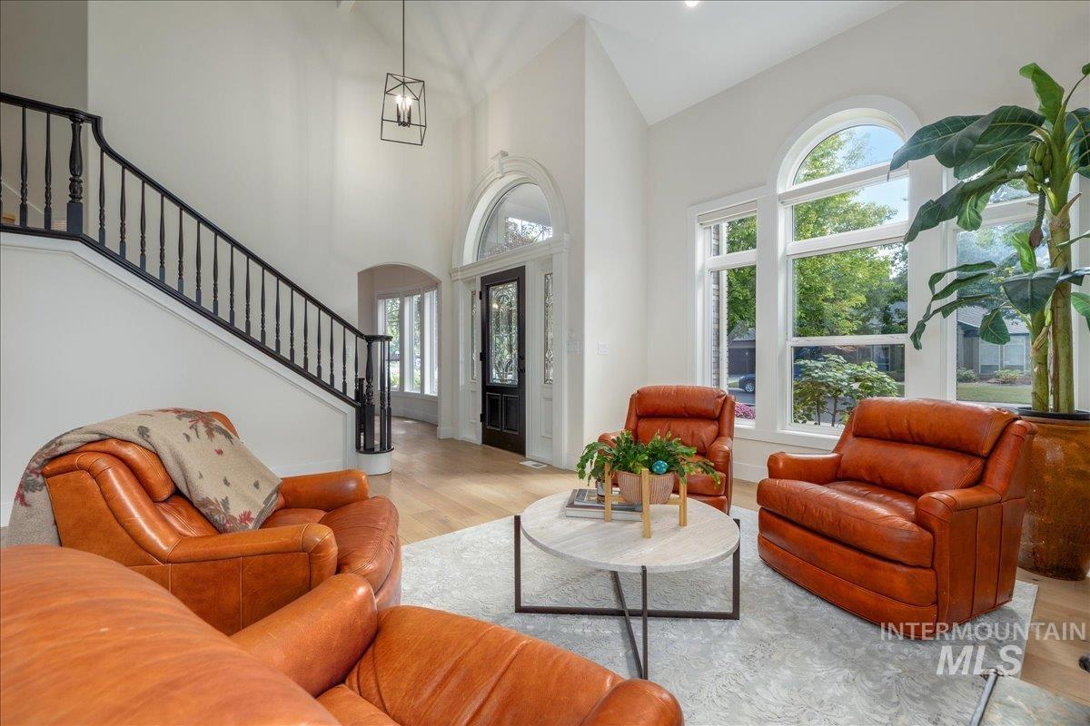 Living room featuring wood finished floors, arched walkways, stairway, and a high ceiling