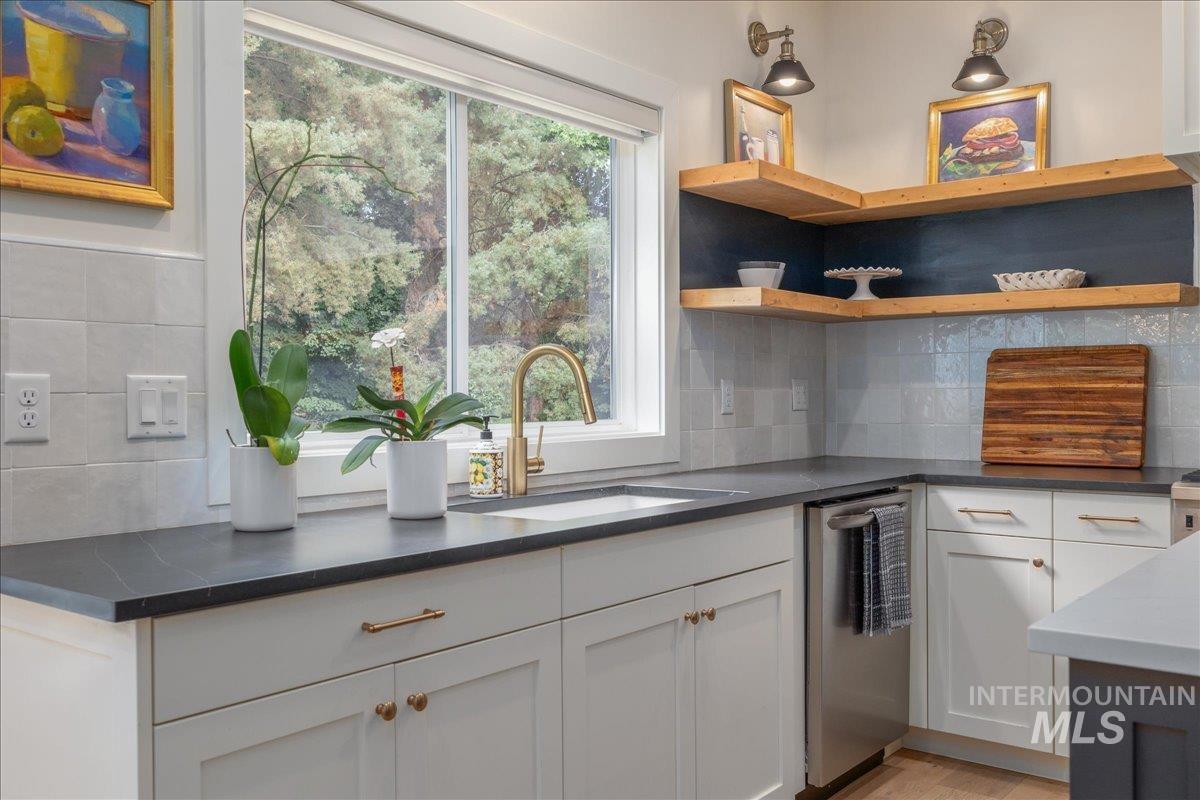 Kitchen with dishwasher, healthy amount of natural light, and white cabinets