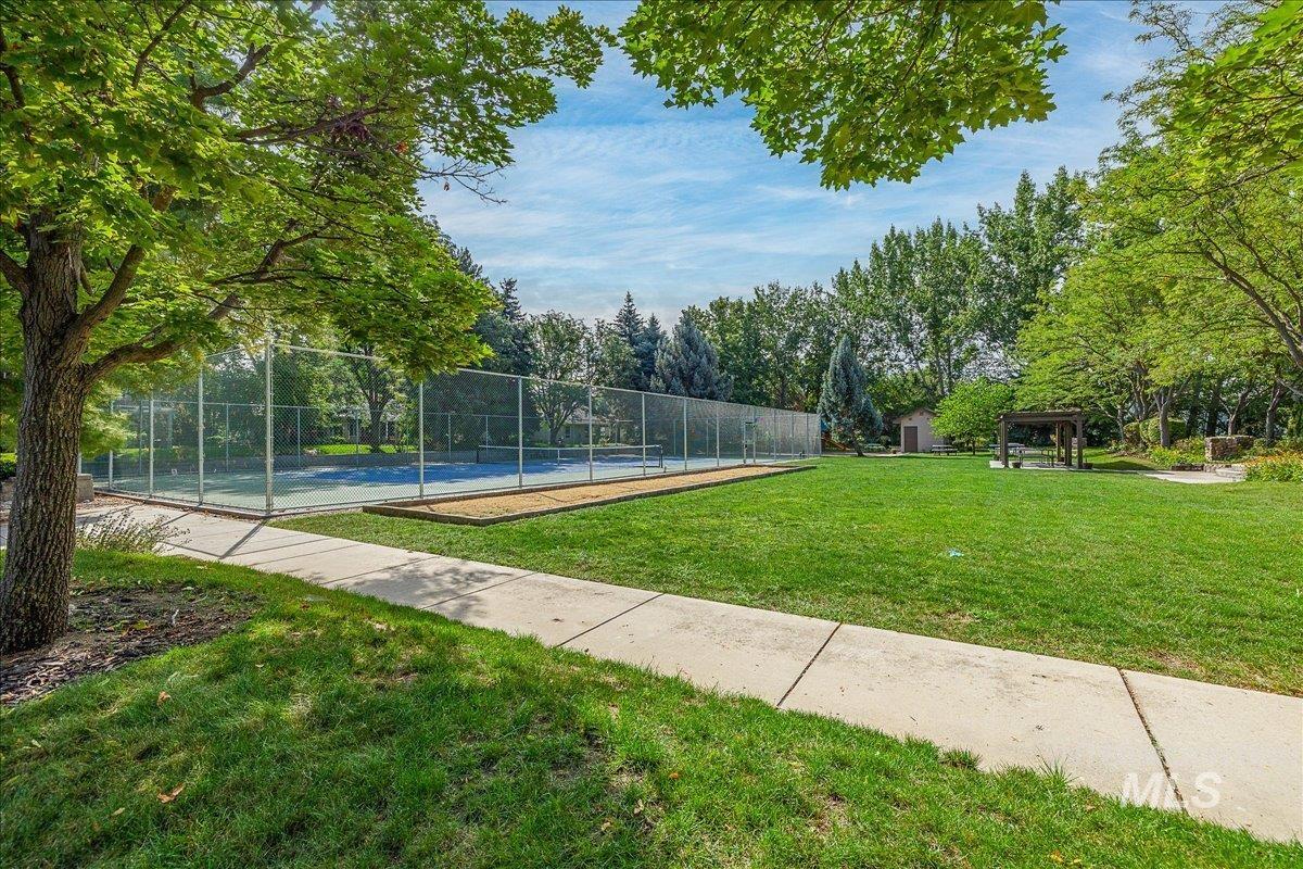 View of community featuring a tennis court and view of scattered trees