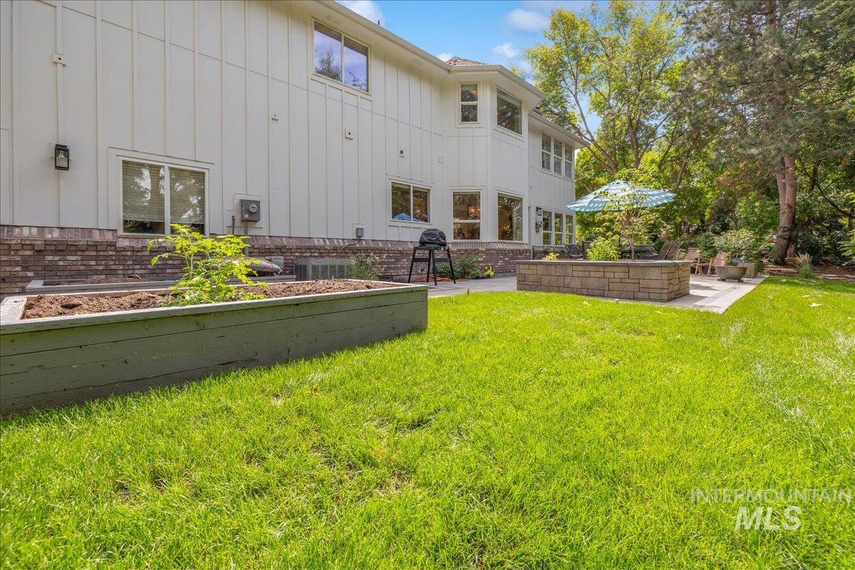 View of grassy yard featuring a patio area and a garden