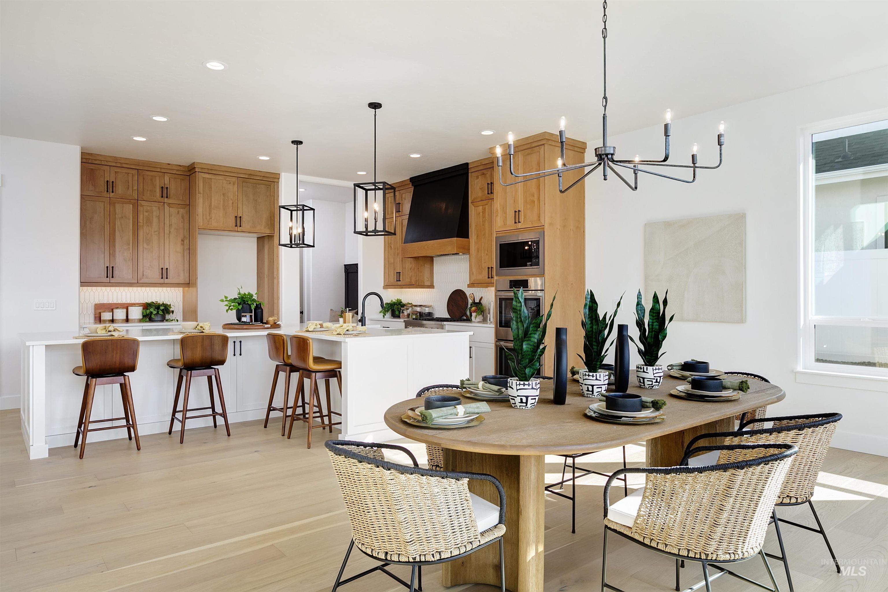 Dining space with a chandelier, light wood-style floors, and recessed lighting