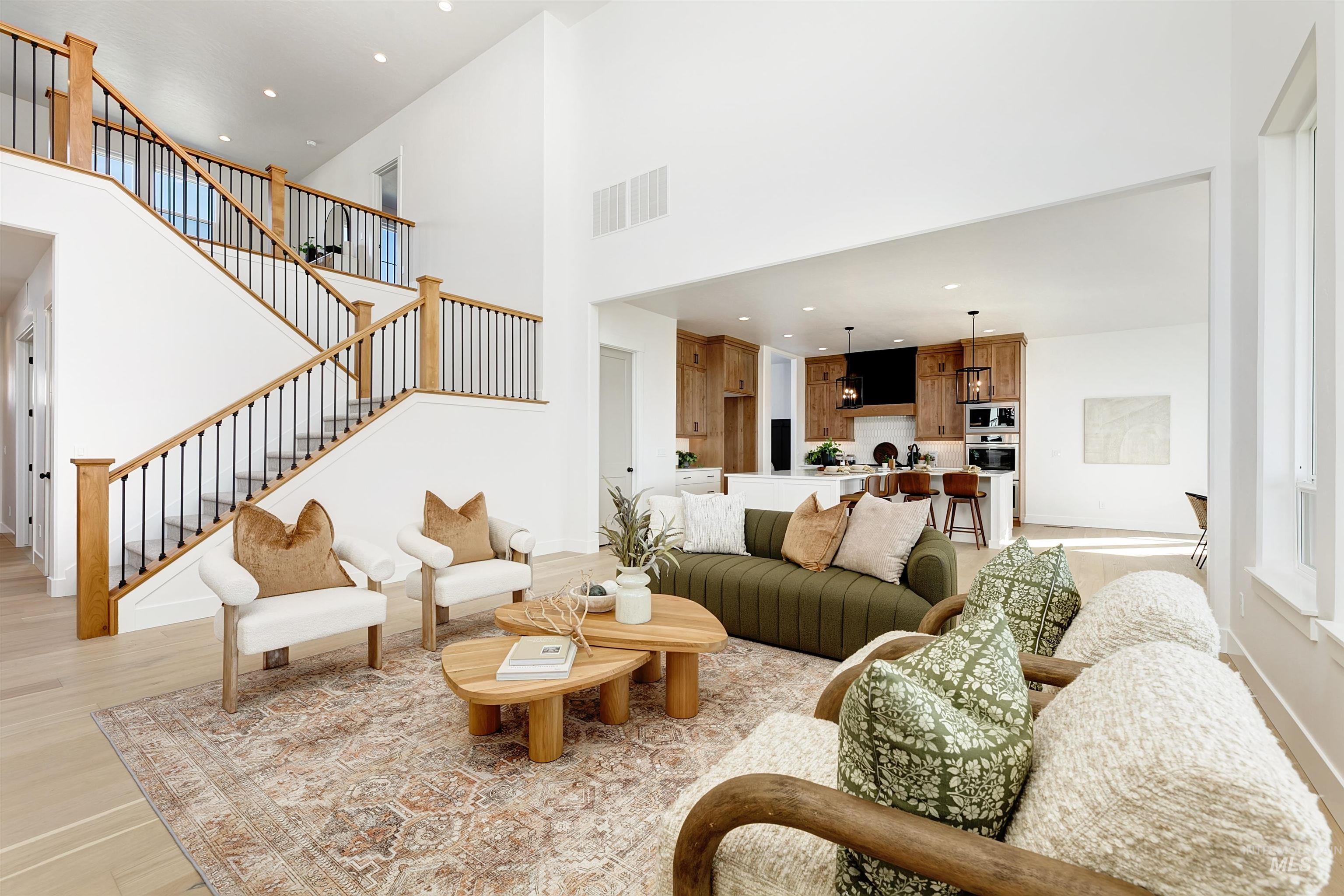 Living room with light wood finished floors, a high ceiling, recessed lighting, and stairs