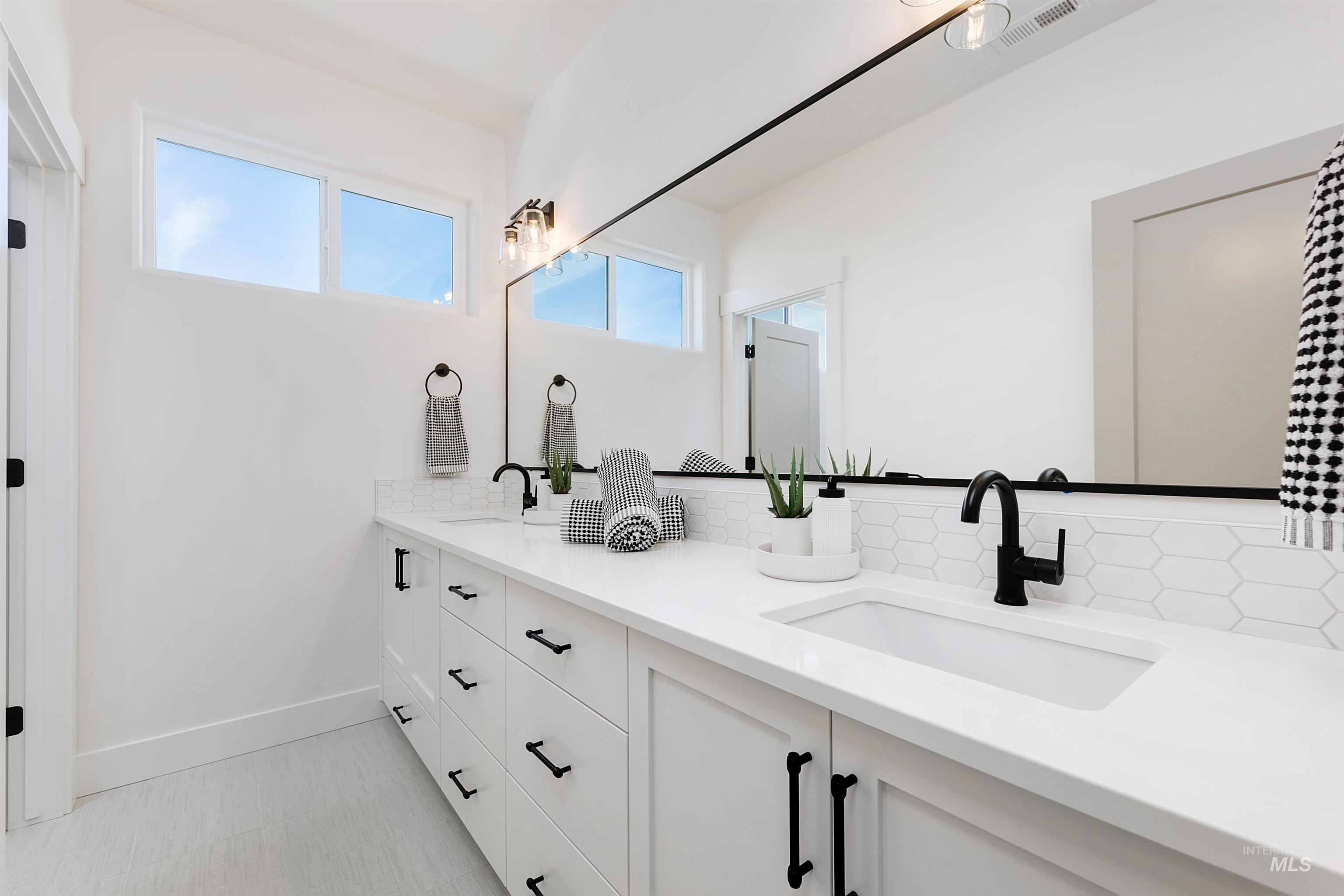 Bathroom featuring double vanity and baseboards