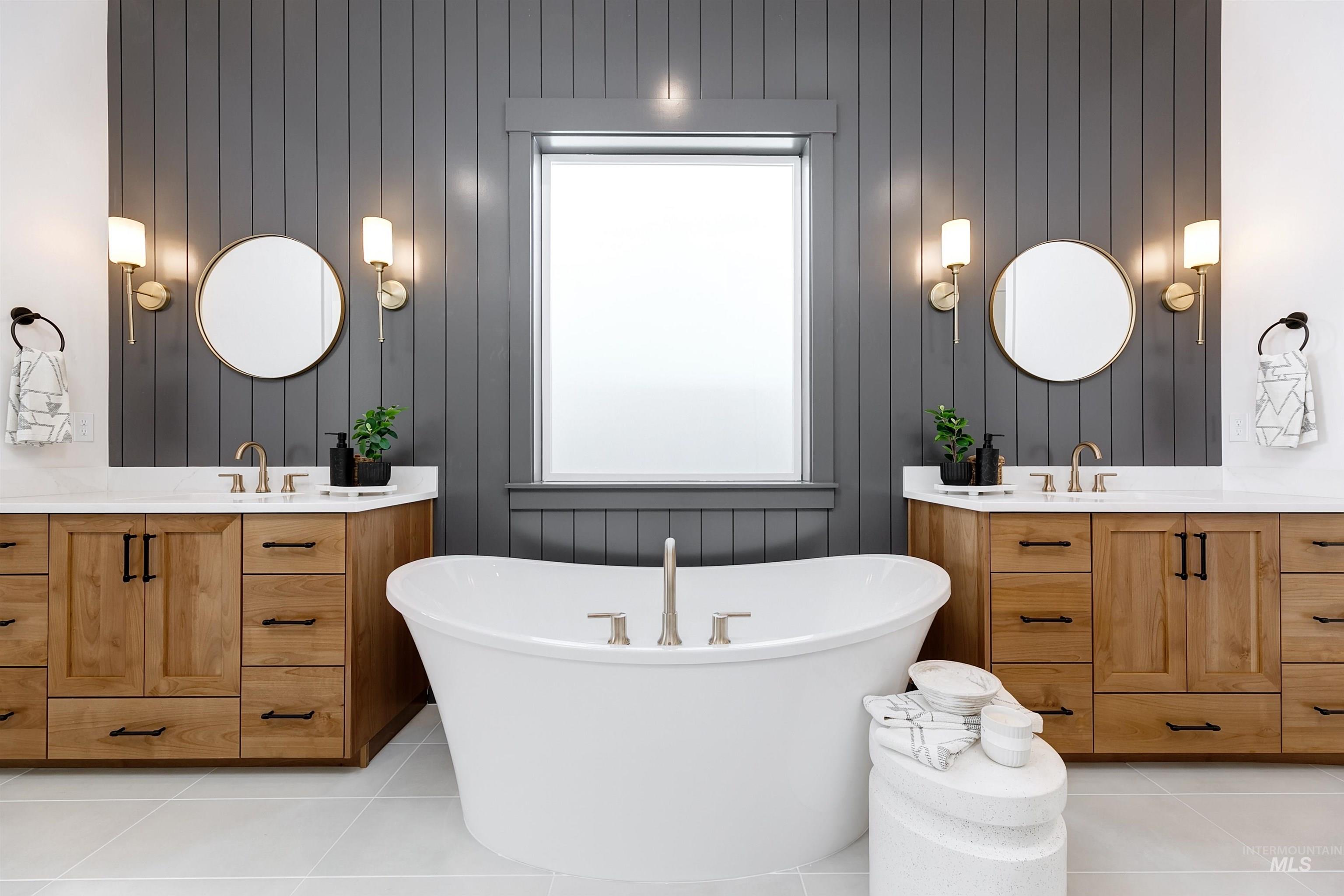 Full bath with two vanities, light tile patterned flooring, and a freestanding tub