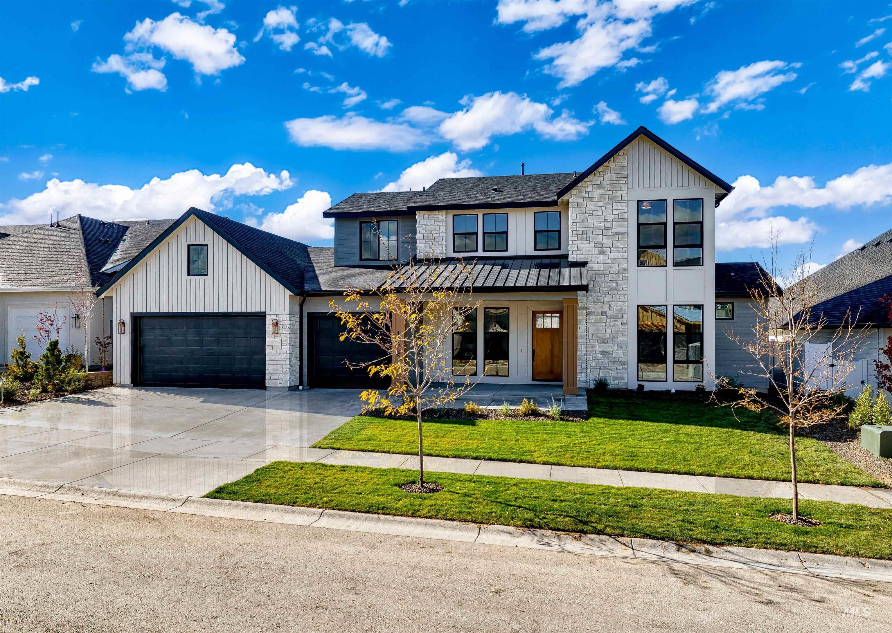 Modern farmhouse featuring a front lawn, driveway, board and batten siding, a shingled roof, and covered porch