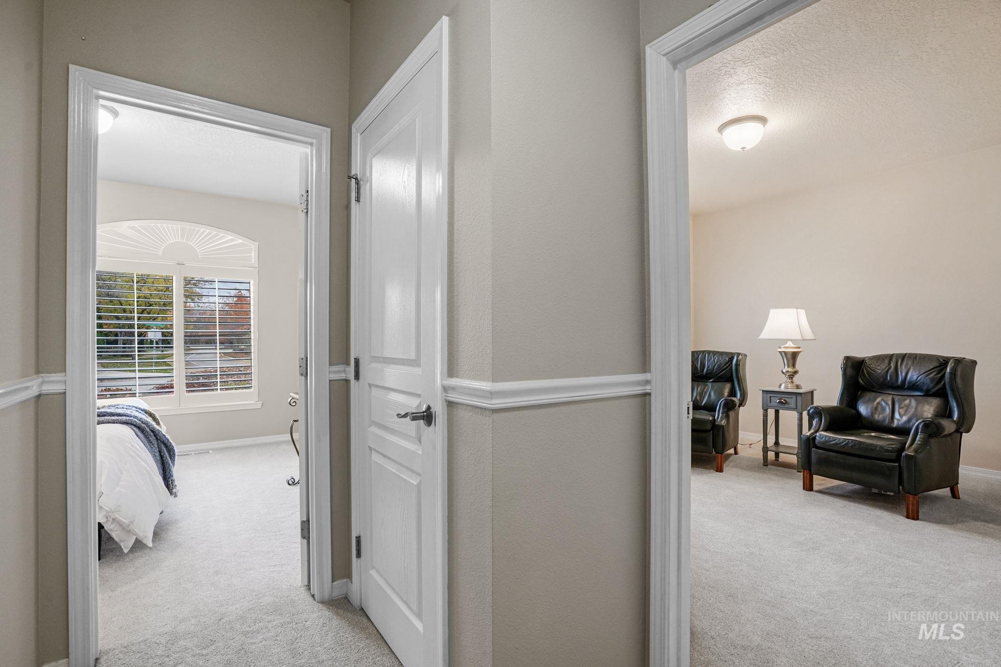Hallway with light carpet and a textured ceiling