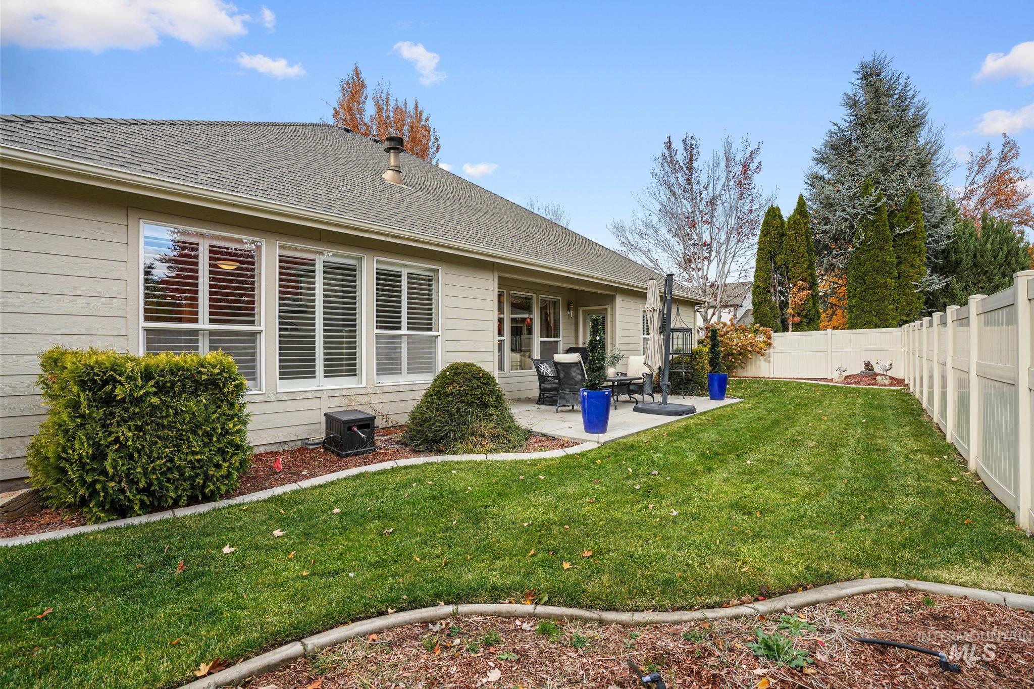 Back of property with a shingled roof, a patio area, and a fenced backyard