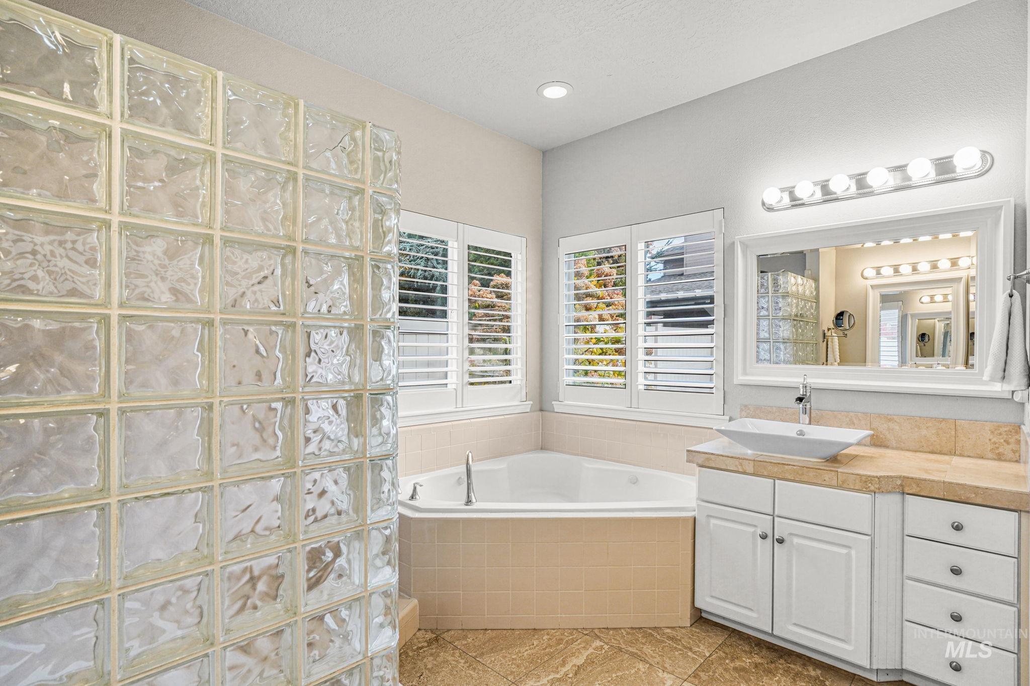 Full bath featuring vanity, a garden tub, light tile patterned floors, and a walk in shower