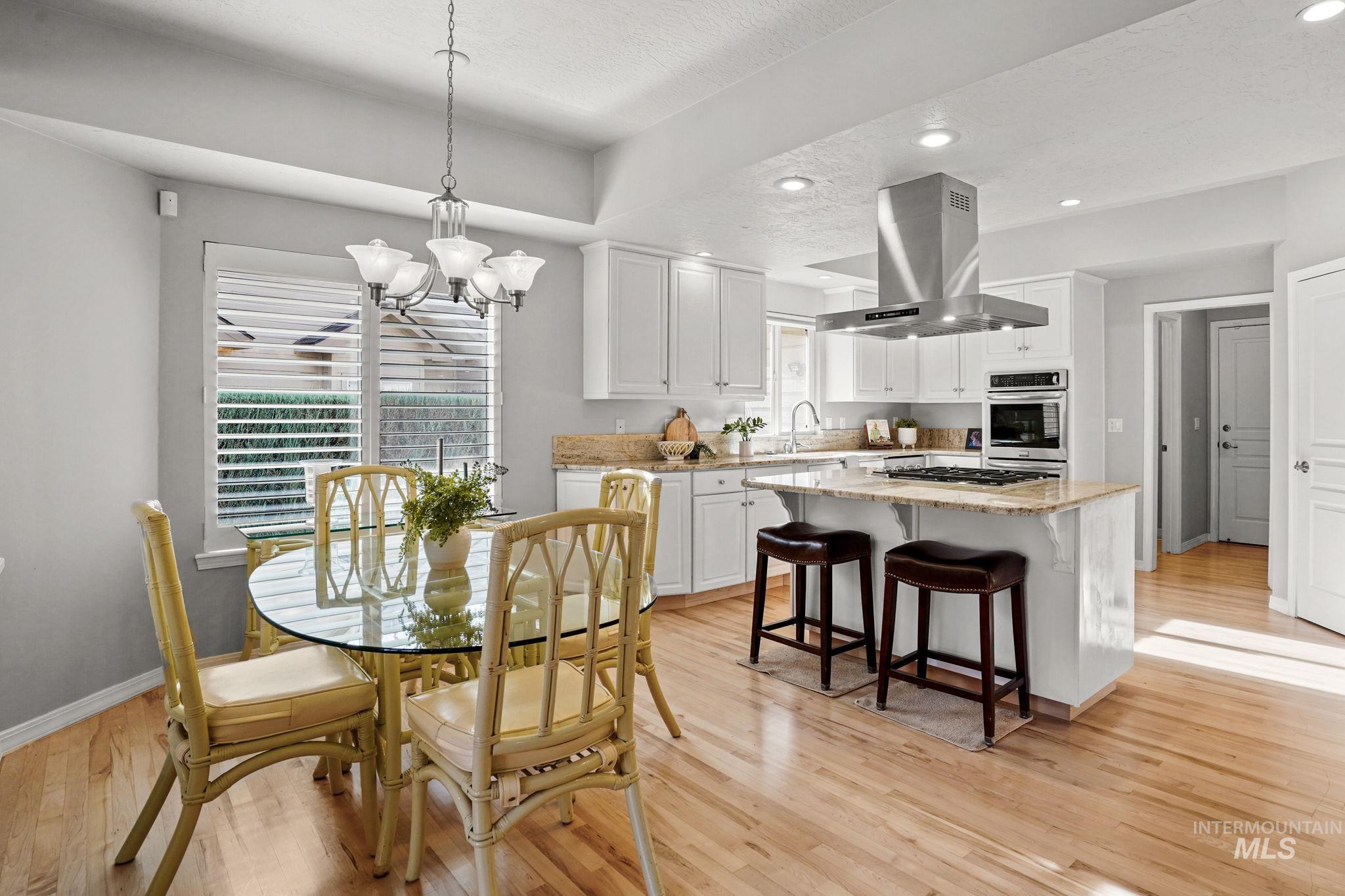 Dining room with light wood-style floors, recessed lighting, a chandelier, and a textured ceiling