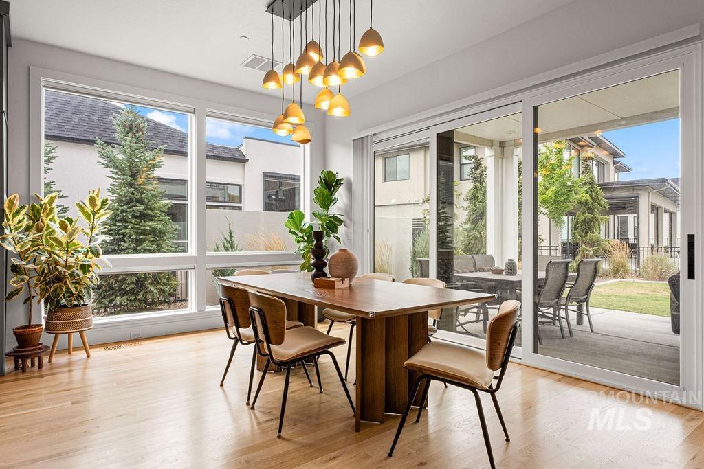 Spacious dining area featuring wood-finish flooring, a contemporary linear chandelier, and expansive windows