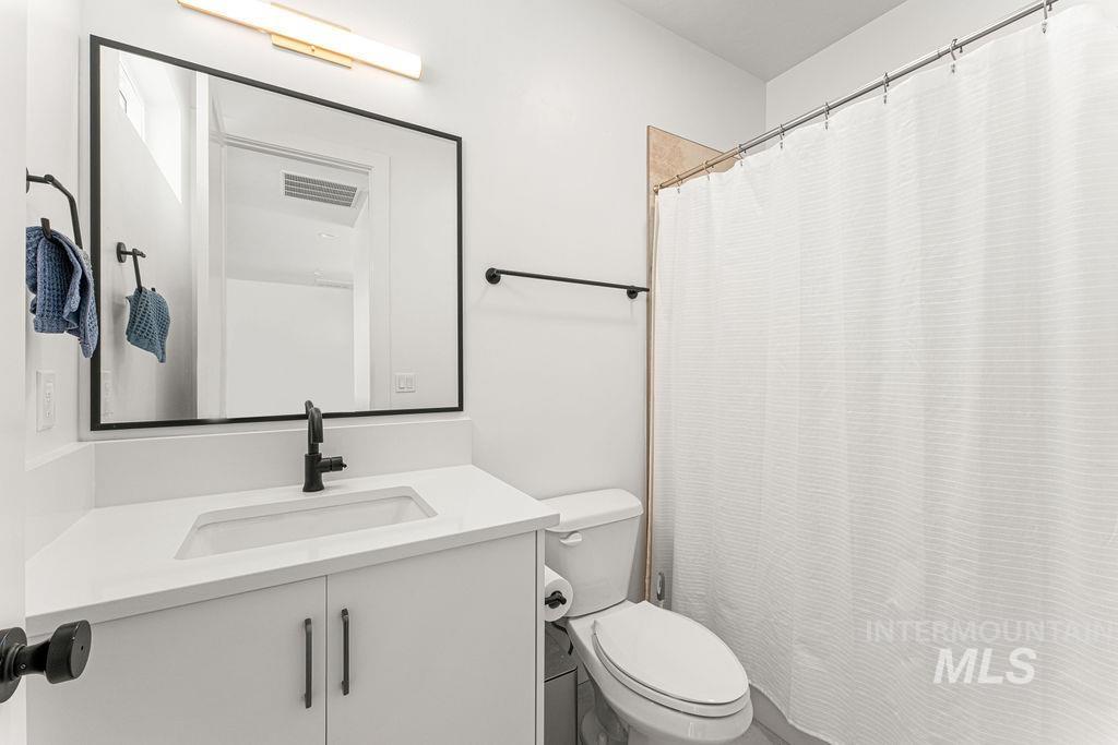 Bathroom vanity featuring a rectangular undermount sink with a matte black faucet, set in a white countertop