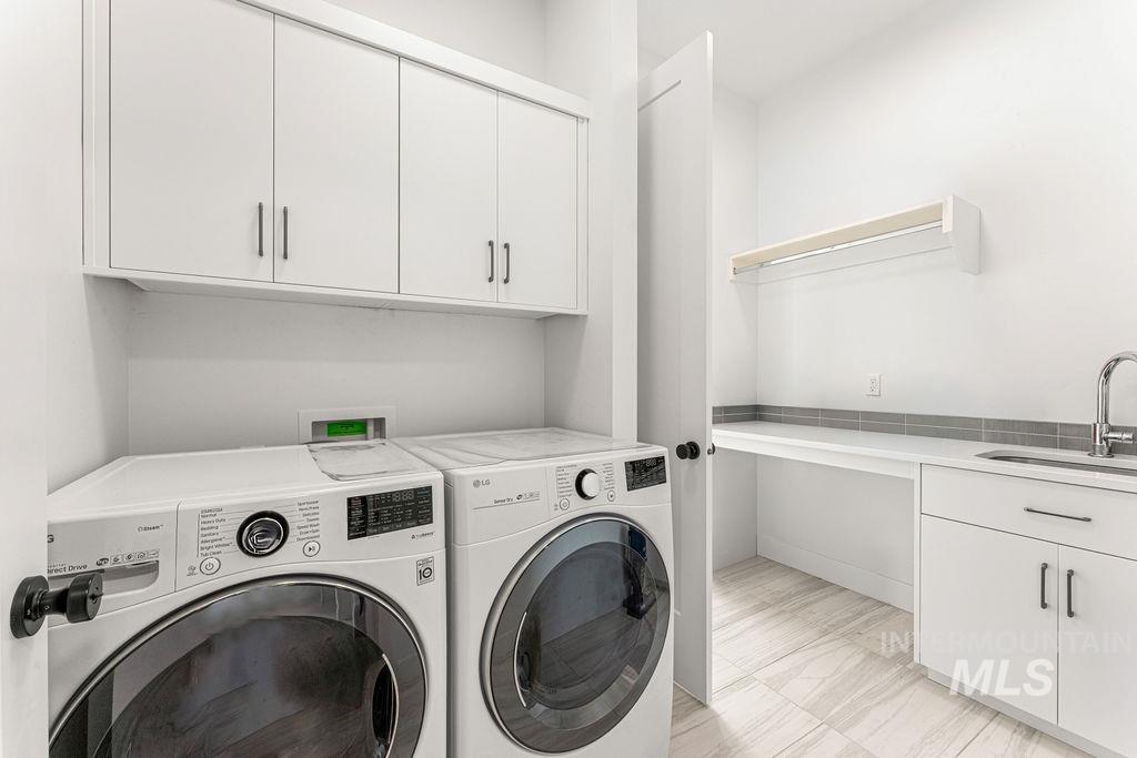 Dedicated laundry room featuring white cabinetry, a built-in sink, a wall-mounted drying rack, a tiled backsplash, and wood-finish flooring