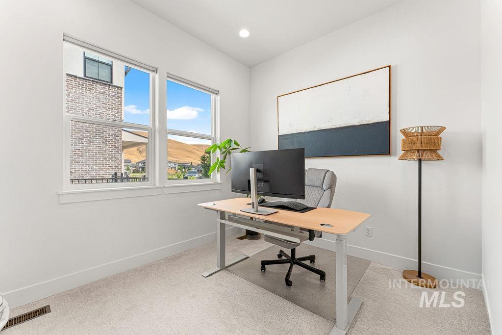 Bright room featuring two large windows with white trim, recessed lighting, and light-colored carpeting