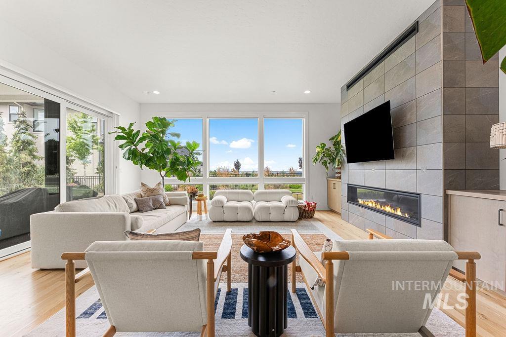 Living room with light wood-finish flooring, a wall-mounted linear fireplace, and integrated built-in cabinetry