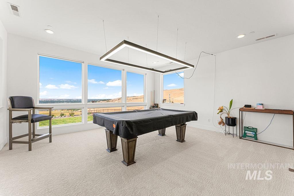Spacious recreation room featuring large picture windows, recessed lighting, and light-toned carpeting