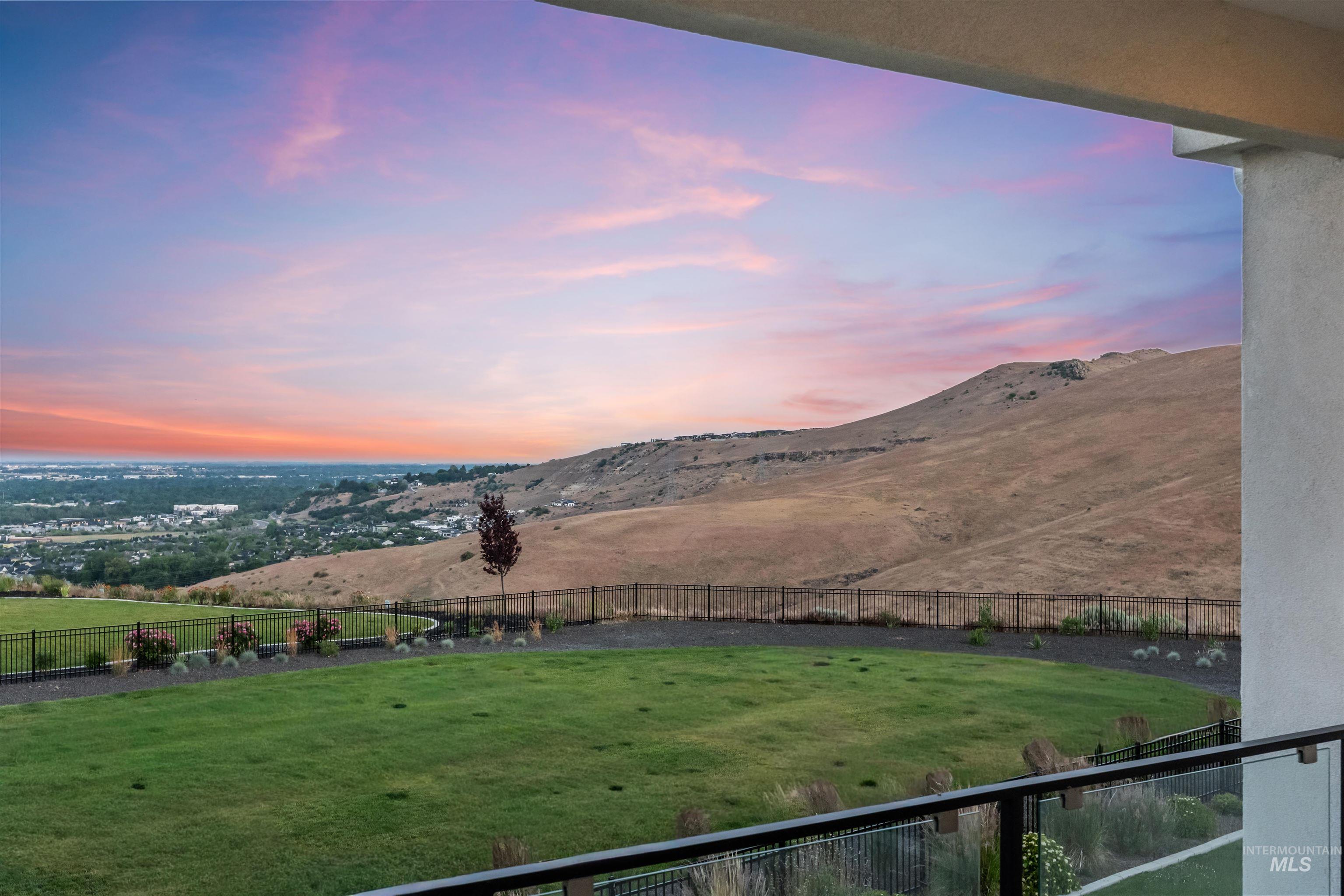 Expansive outdoor space featuring a manicured lawn, established landscaping, and a distant city panorama