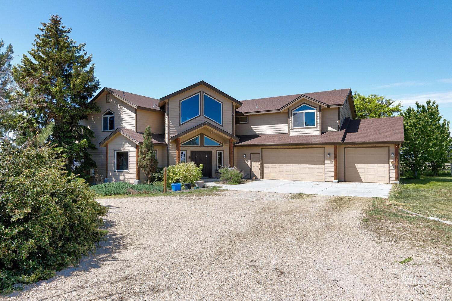 View of front of home with dirt driveway, an attached garage, a garage, and a shingled roof