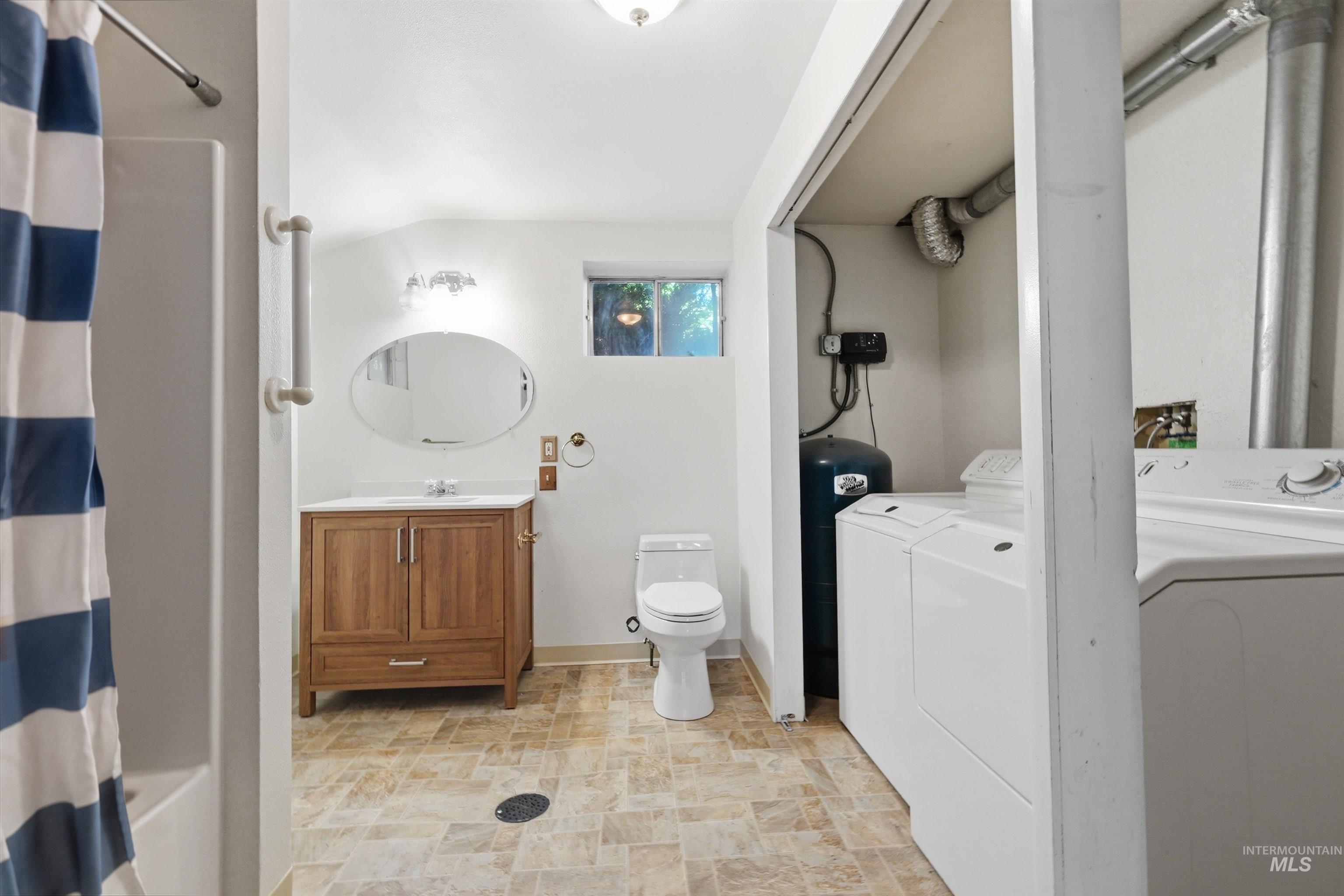 Bathroom featuring a wood-finish vanity with an oval mirror and overhead lighting