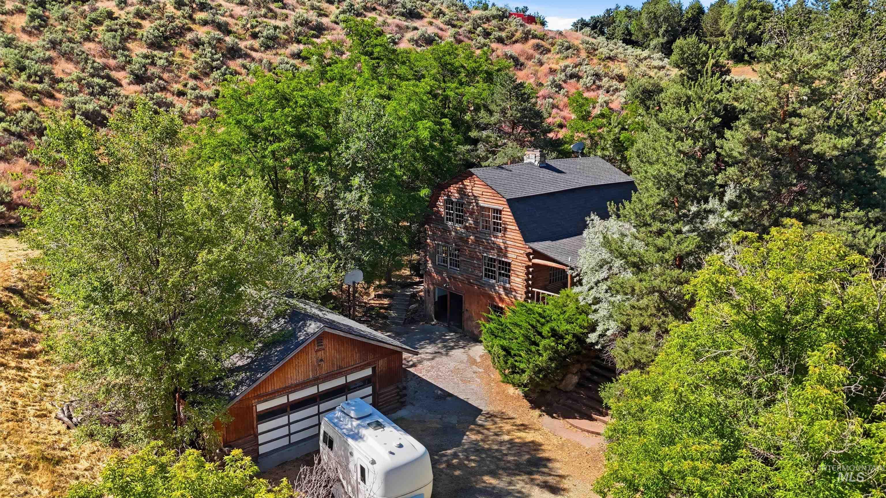 Log cabin-style residence featuring a dark shingle roof and a prominent stone chimney