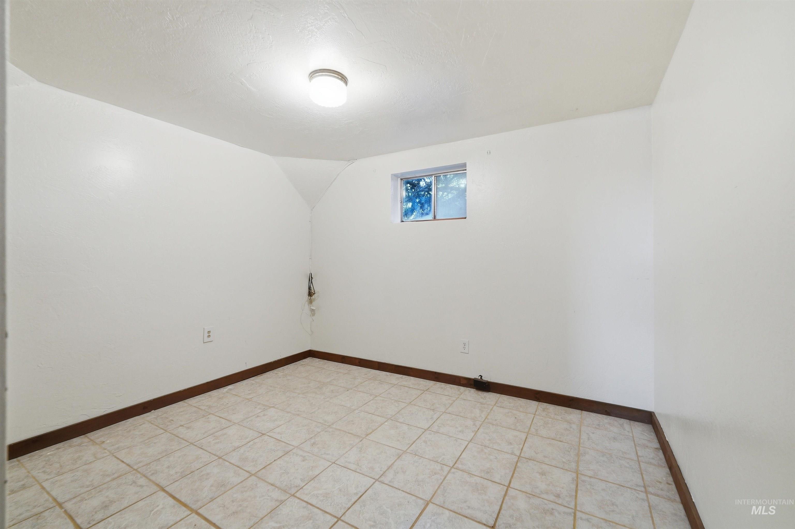 Room featuring light-colored tile flooring, white walls, and a single ceiling-mounted light fixture