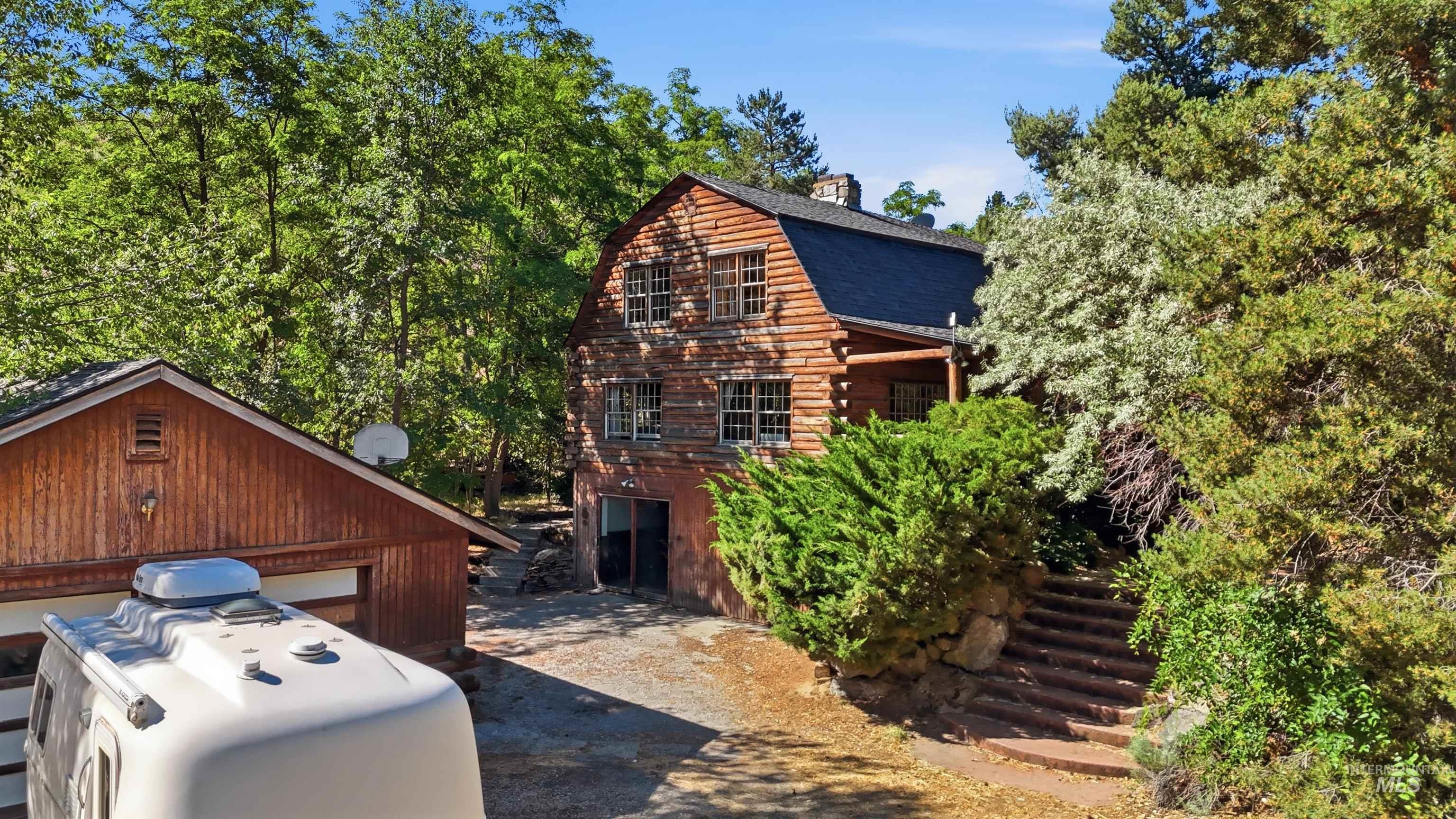 Wood-sided residence featuring a dark shingle roof, chimney, and multiple windows