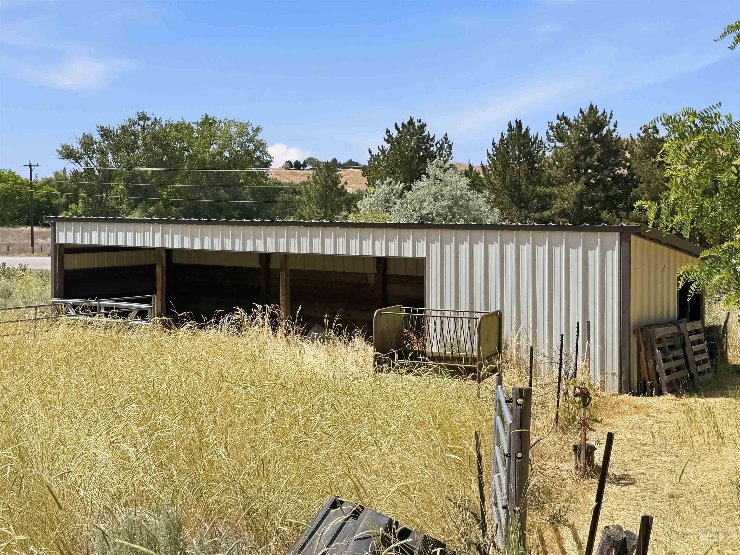Metal-sided barn structure with open-front stalls and a sloped roof