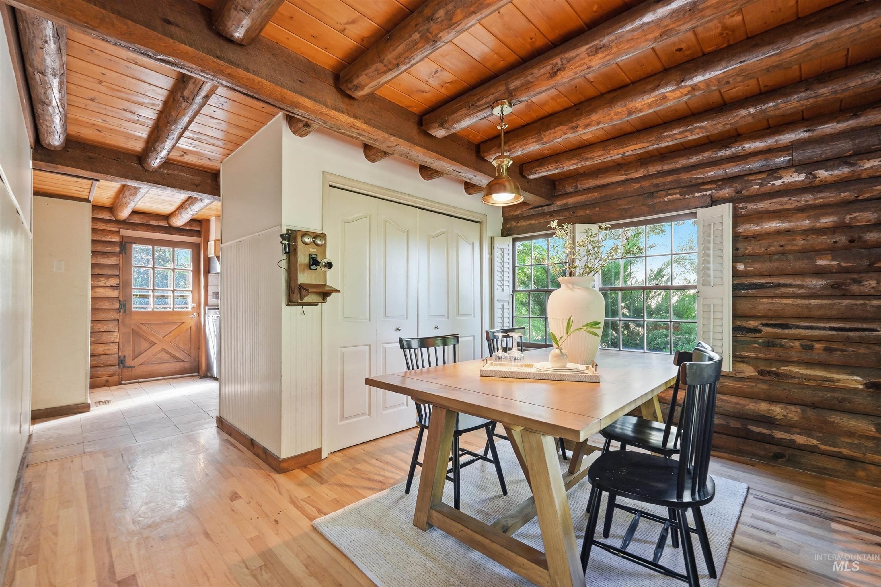 Dining area featuring natural wood log walls and exposed log beam ceiling