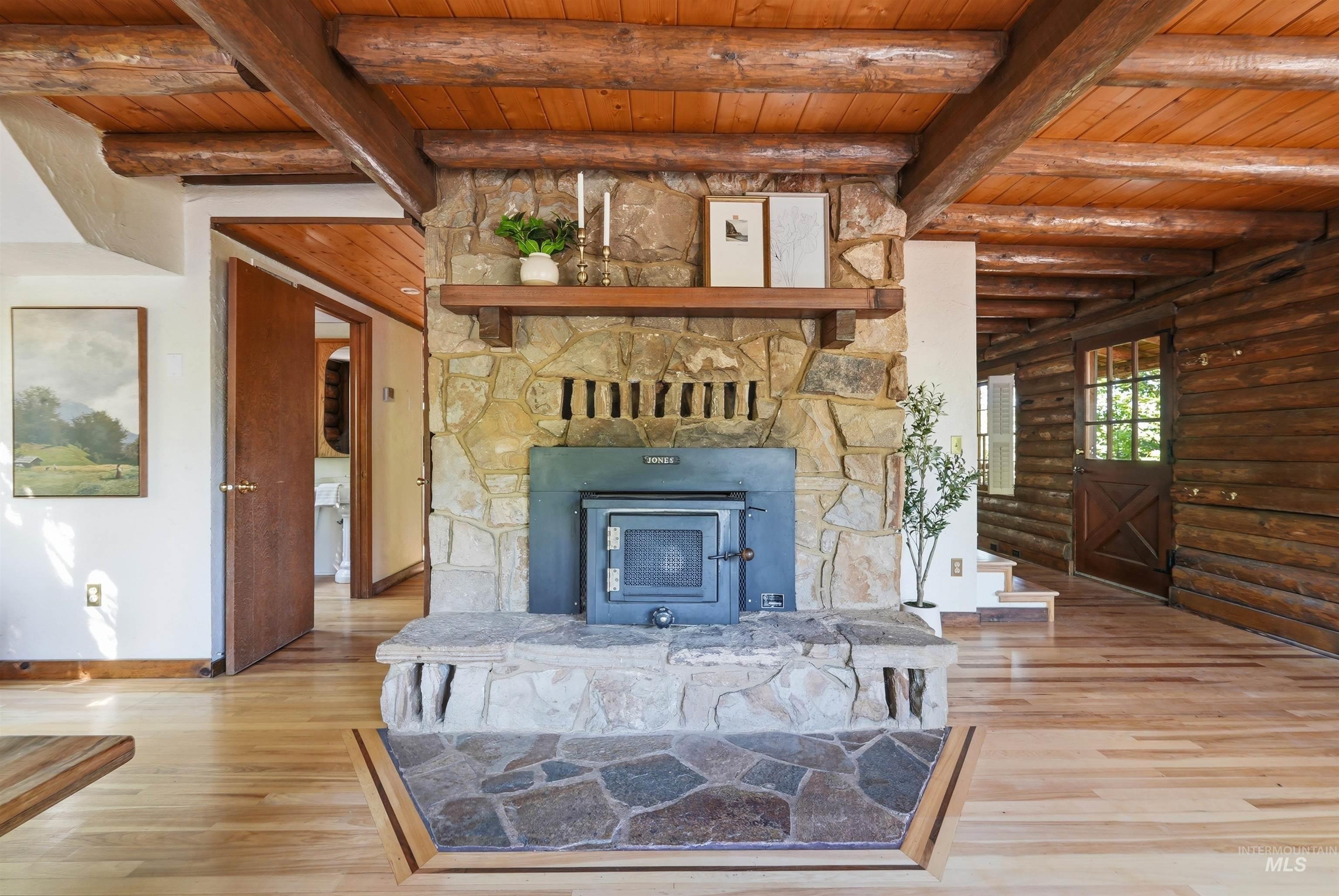 Central stone fireplace with integrated wood-burning stove and hearth, complemented by a natural wood mantel