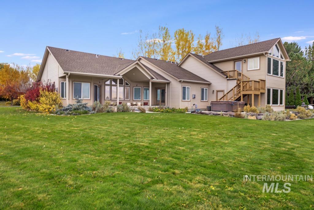 Back of property with stairs, a lawn, a hot tub, and a patio