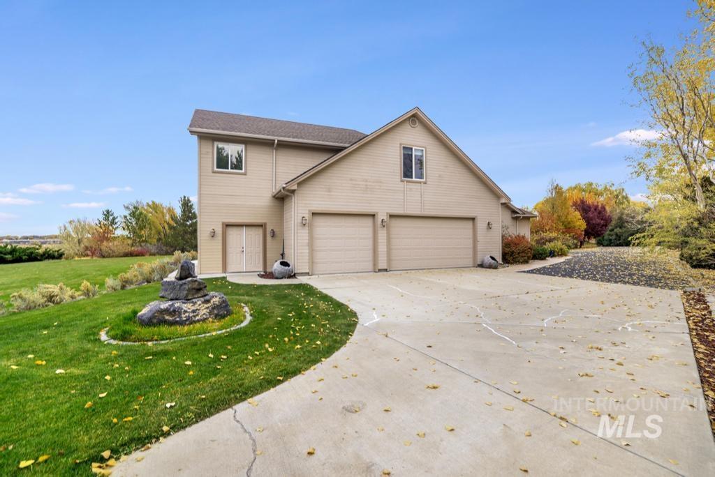 View of front facade featuring concrete driveway, a garage, and a front lawn