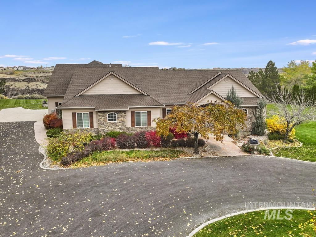 View of front of house featuring a shingled roof, stone siding, and driveway