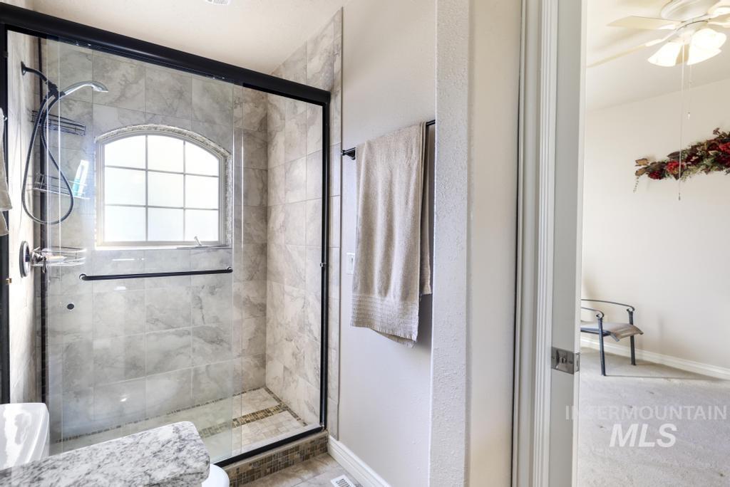 Full bath featuring a shower stall and ceiling fan
