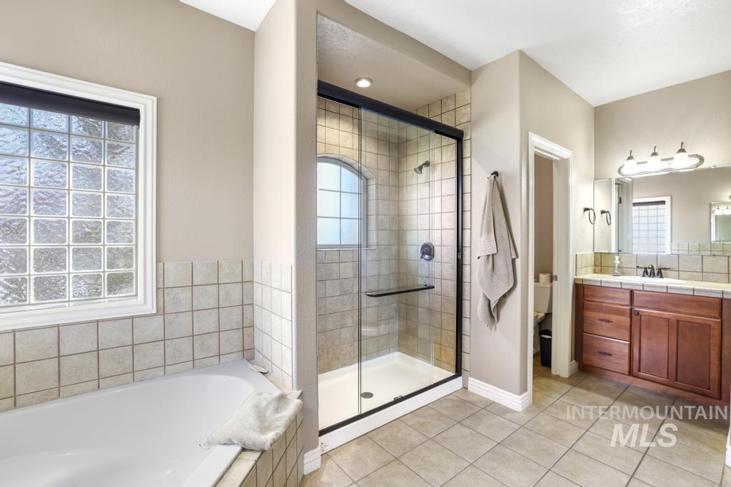 Bathroom with vanity, a garden tub, a shower stall, and light tile patterned floors