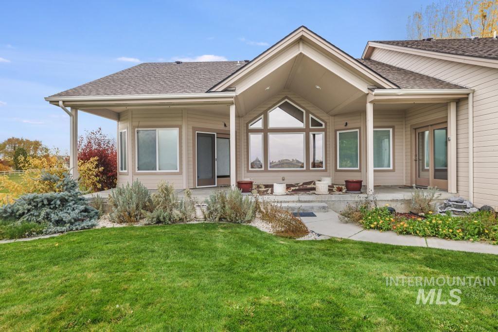 Back of house featuring a lawn, a shingled roof, and a patio area