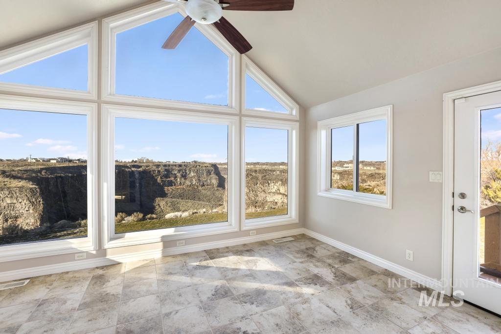 Unfurnished sunroom featuring lofted ceiling and baseboards