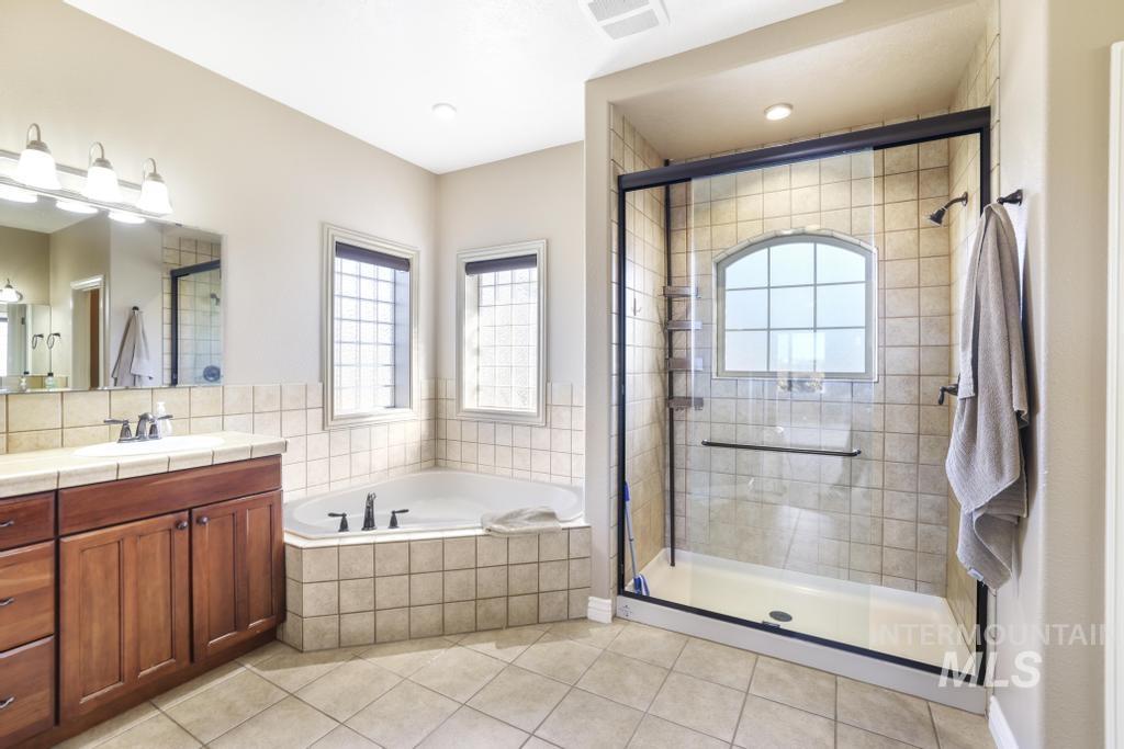 Bathroom with vanity, a garden tub, a shower stall, and light tile patterned flooring